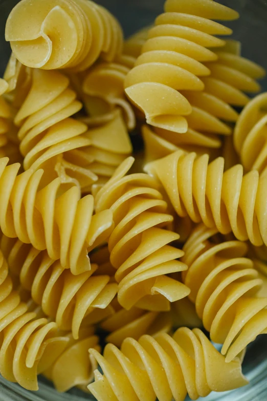 a bowl filled with pasta sitting on top of a table, many teeth, up-close, golden spirals, up close