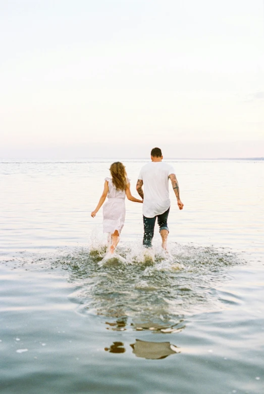 a man and a woman are walking in the water, unsplash contest winner, beautifully soft lit, sydney hanson, plain background, summer feeling