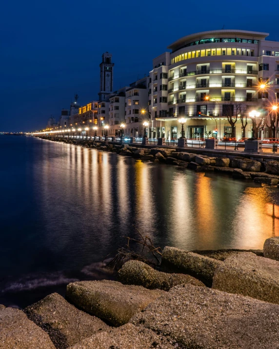 a large body of water next to a city, pexels contest winner, street lighting, next to the sea, lgbtq, thumbnail