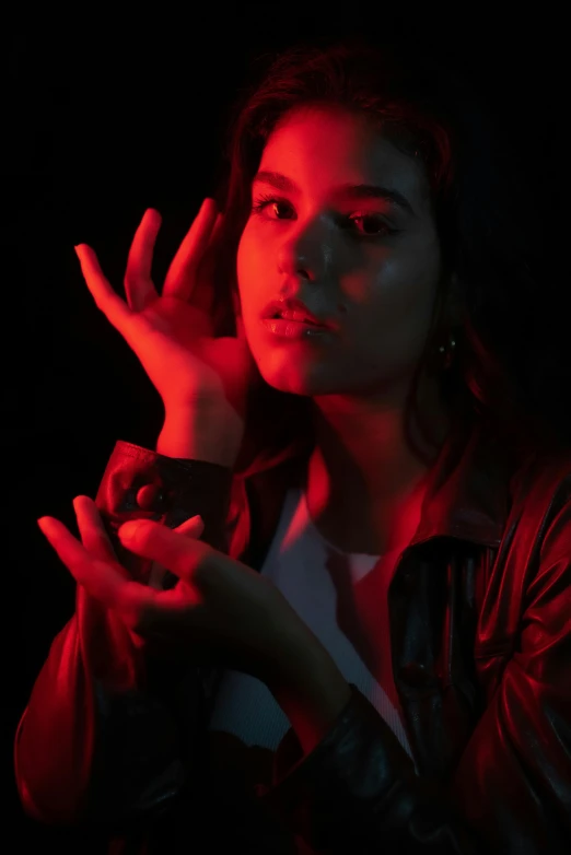 a woman holding a cell phone up to her face, an album cover, inspired by Elsa Bleda, trending on pexels, glowing hands, black and red, teenage girl, portrait lighting