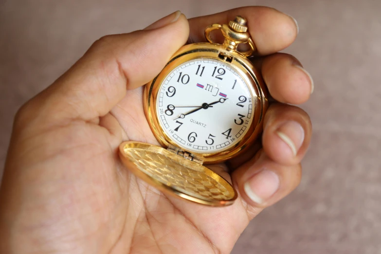 a person holding a pocket watch in their hand, by Mym Tuma, hurufiyya, gold plated, photo taken in 2 0 2 0, ( ultra realistic ), mini model