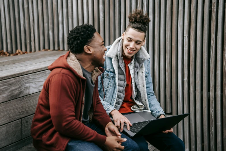 a man and woman sitting on a bench with a laptop, trending on pexels, black teenage boy, smiling at each other, brunette boy and redhead boy, guide