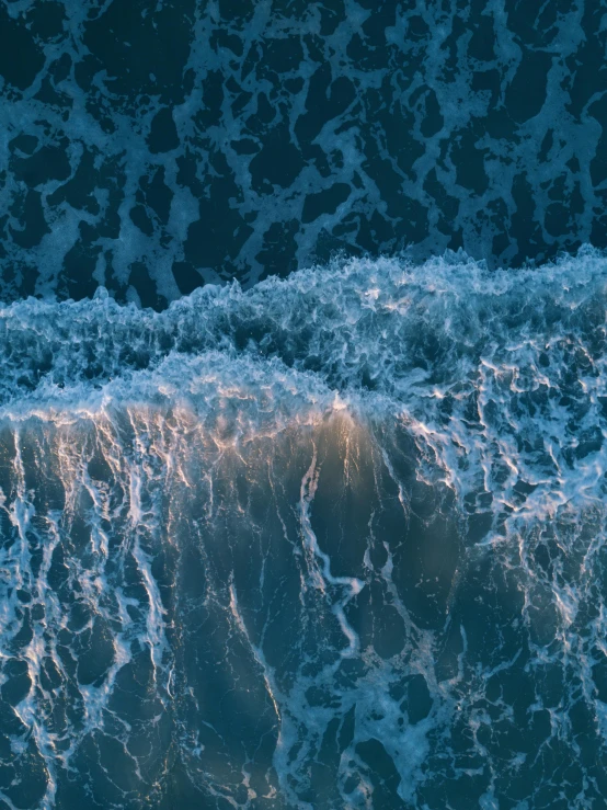 a person riding a surfboard on top of a wave, in the ocean, from above, glowing water with caustics, unsplash 4k