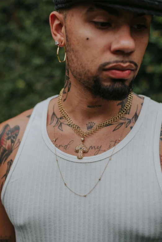 a close up of a person wearing a hat, an album cover, inspired by Byron Galvez, renaissance, wears a egyptian ankh necklace, wearing a low cut tanktop, gold chain necklace, arms covered in gang tattoo