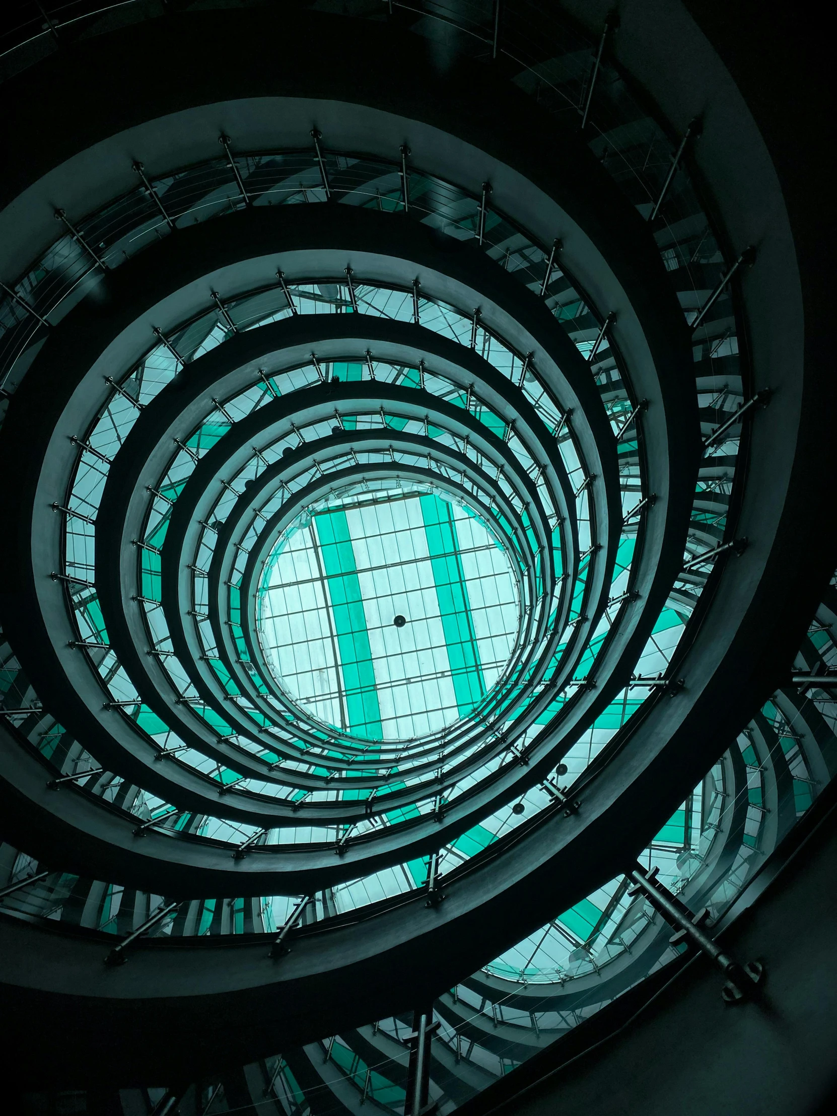 a spiral staircase in the middle of a building, inspired by Alexander Rodchenko, unsplash contest winner, teal electricity, glass domes, panoramic anamorphic, circular towers