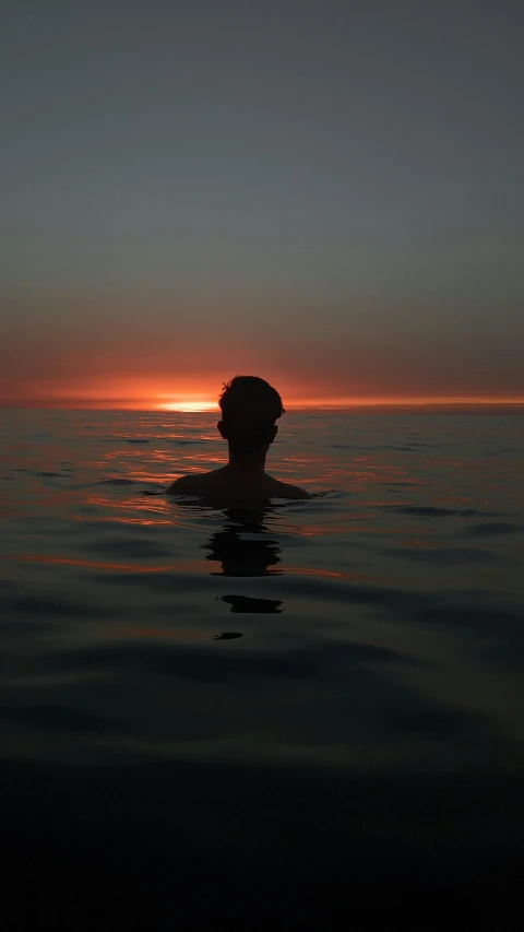 a person swimming in the ocean at sunset, an album cover, profile image, high quality photo, matt rhodes, ((sunset))