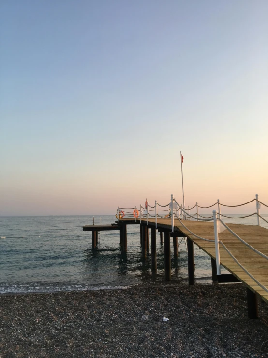 a pier sitting on top of a beach next to the ocean, during a sunset, profile image, mediterranean fisher village, 💋 💄 👠 👗