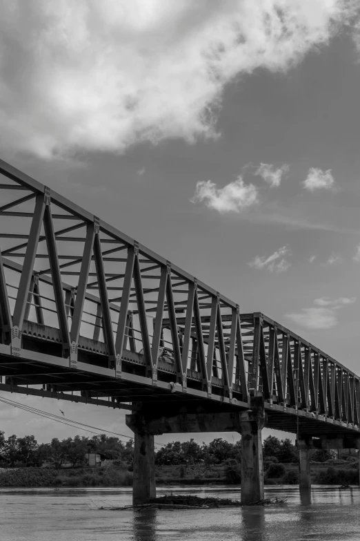 a black and white photo of a train crossing a bridge, a black and white photo, by Dave Melvin, in louisiana, blue sky, 2022 photograph, f / 8