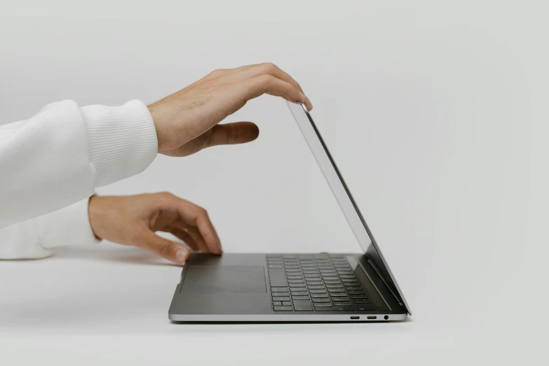 a close up of a person using a laptop, by Carey Morris, pexels, on a gray background, grey metal body, pointing, background image