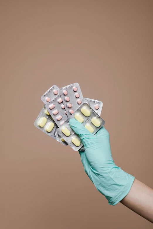 a person in blue gloves holding a bunch of pills, pastell colours, 3 - piece, surgical impliments, jen atkin