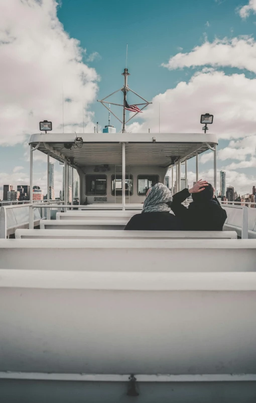 a couple of people sitting on top of a boat, unsplash, low quality photo, long distance photo, city views, ship interior