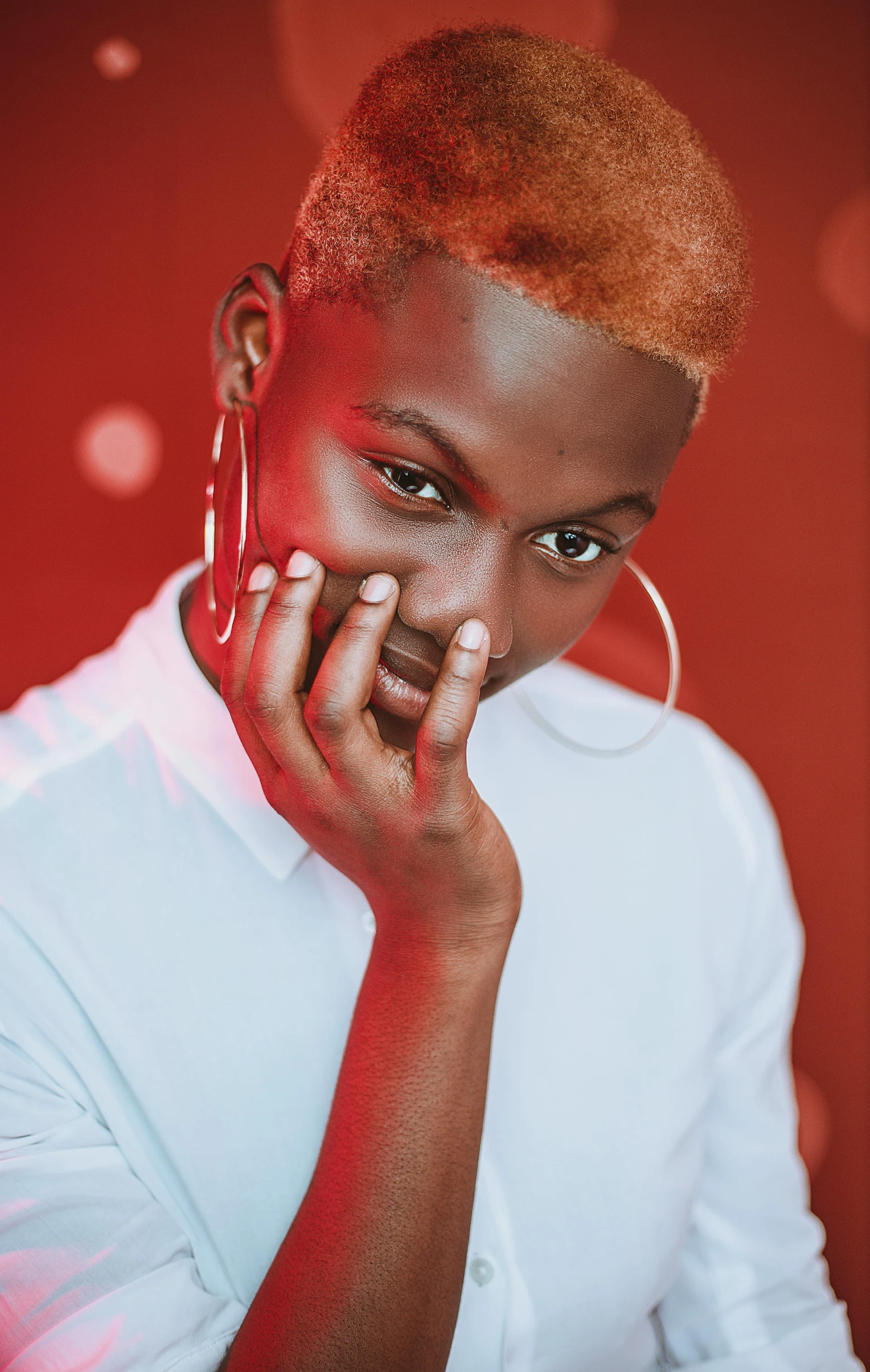 a woman in a white shirt posing for a picture, an album cover, by Cosmo Alexander, trending on pexels, black teenage boy, red hue, wearing silver hair, hand on his cheek