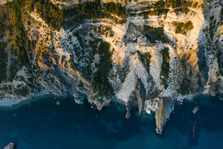 a man standing on top of a cliff next to a body of water, pexels contest winner, renaissance, aerial view cinestill 800t 18mm, apulia, panels, cliff side at dusk