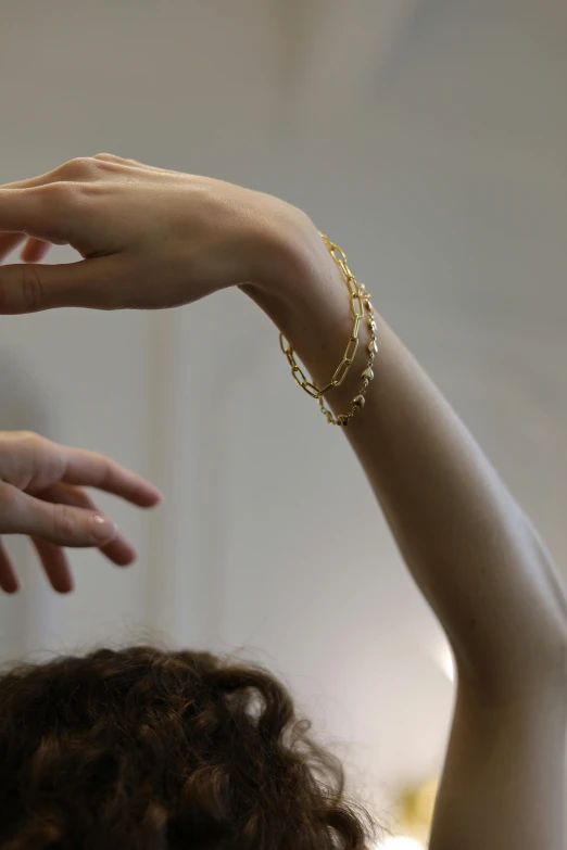 a close up of a person with their hands in the air, by Nina Hamnett, rococo, gold bracelet, light from right, dainty, tall