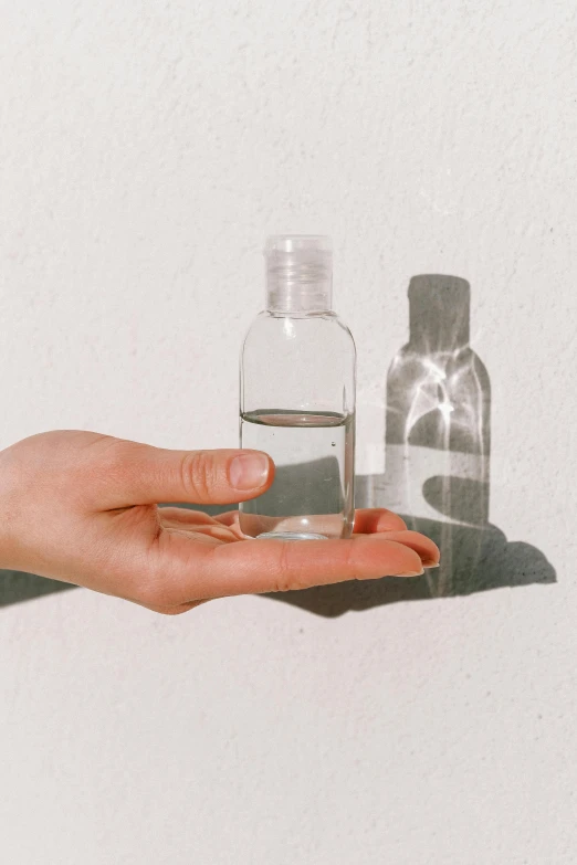 a person holding a bottle of water in their hand, by Nicolette Macnamara, minimalism, clear makeup, instagram post, smol, evenly spaced