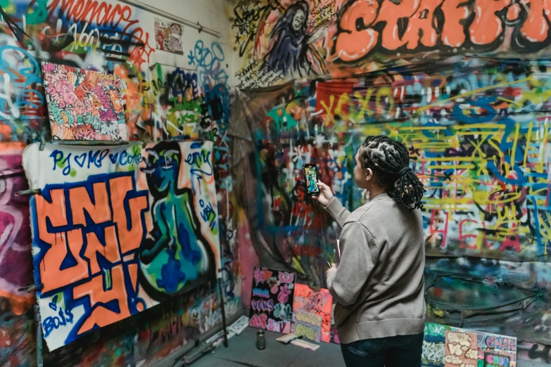 a woman standing in front of a wall covered in graffiti, by artist, pexels contest winner, instagram post, painting a canvas, stood in a tunnel, australian