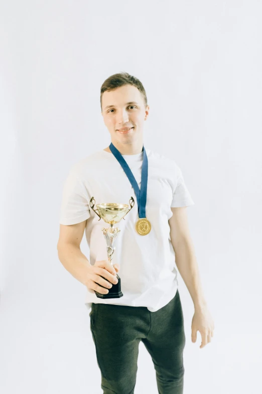 a man in a white shirt holding a trophy, by Adam Marczyński, pexels contest winner, 1 6 years old, plain background, gold medal, official photo