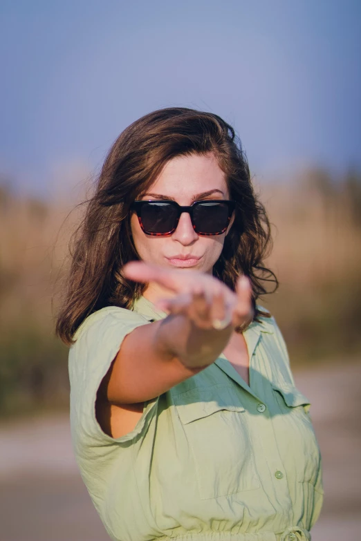 a woman in a green shirt throwing a frisbee, unsplash, designer sunglasses, pointing index finger, square, portait image