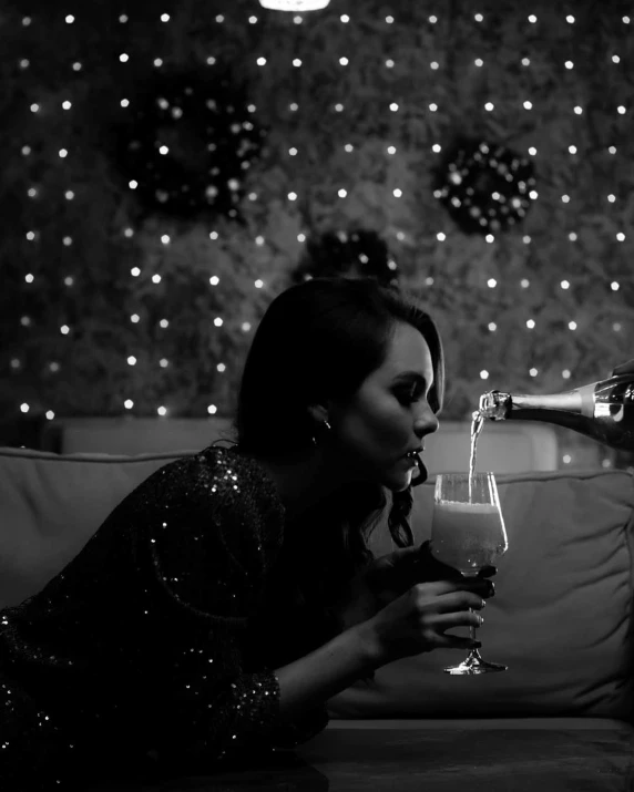 a woman sitting on a couch holding a wine glass, a black and white photo, by Adam Marczyński, pexels contest winner, night life, cgsociety 8k, bubbly, romance