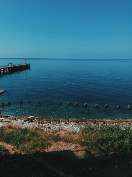 a pier in the middle of a body of water, black sea, panoramic shot, shot on iphone 1 3 pro, ultrawide lens”