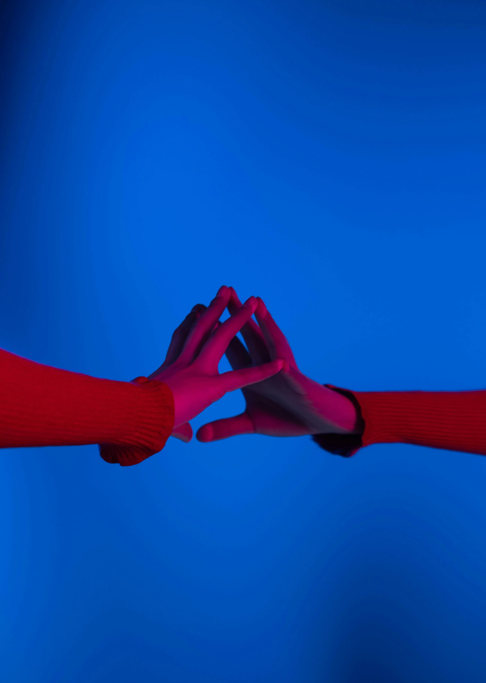 two hands holding each other in front of a blue background, by Doug Ohlson, vibrant red 8k, ignant, ultra high res, magenta and blue