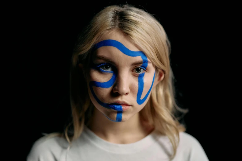 a girl with blue paint on her face, an album cover, by Adam Marczyński, trending on pexels, sydney sweeney, greta thunberg, facial tribal markings, miro petrov