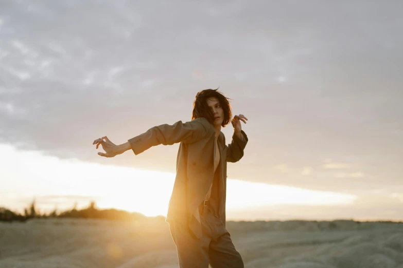 a man standing on a skateboard in the middle of a field, an album cover, by Emma Andijewska, unsplash, magical realism, hozier, she is dancing, sun down golden hour, androgynous person