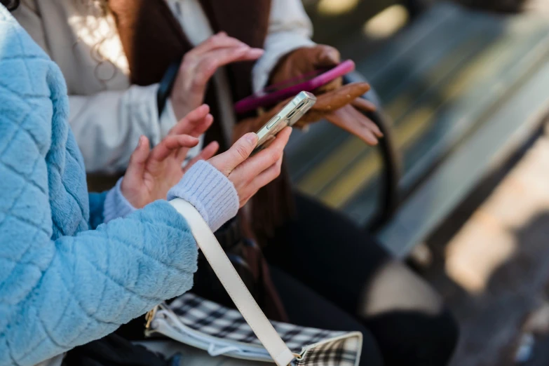 two women sitting on a bench looking at their cell phones, trending on pexels, hands with five fingers, avatar image, holding a gold bag, a group of people