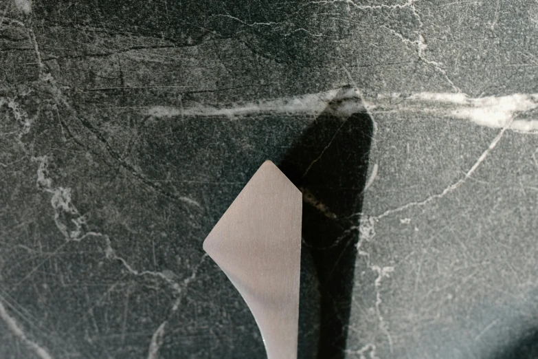 a wooden spoon sitting on top of a marble counter, inspired by Robert Mapplethorpe, graffiti, grey, polished metal, slate, large tail