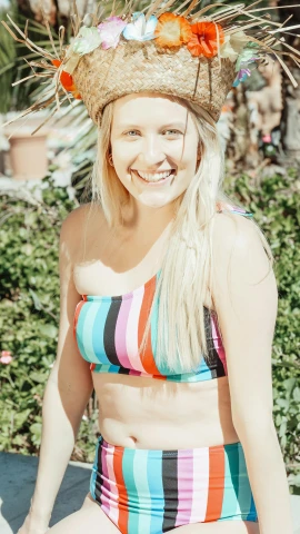 a woman sitting on a bench with a hat on her head, a colorized photo, unsplash, wearing two - piece swimsuit, smiling down from above, wearing a cropped top, blond