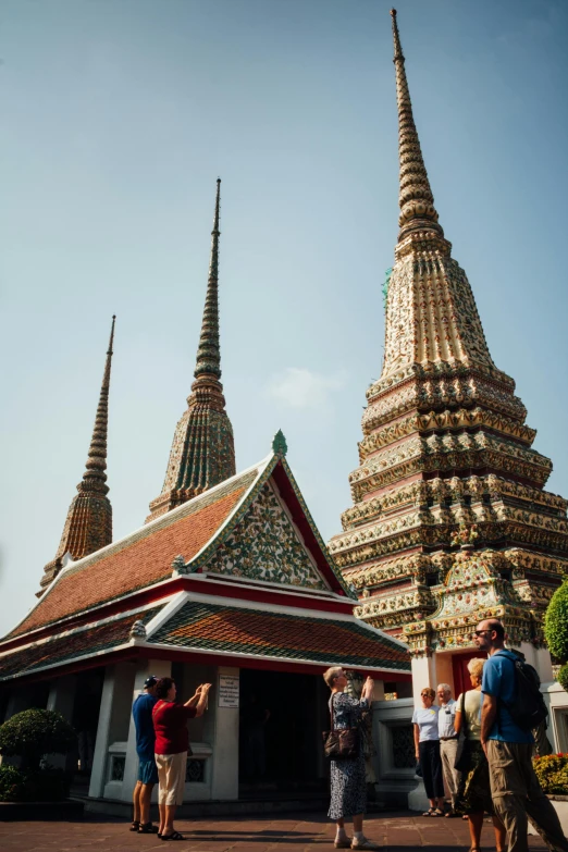 a group of people standing in front of a building, thai architecture, black domes and spires, lead - covered spire, mossy buildings