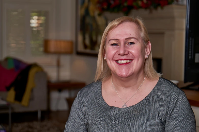 a woman sitting at a table with a plate of food, smiling for the camera, profile image, darren bartley, academy headmaster