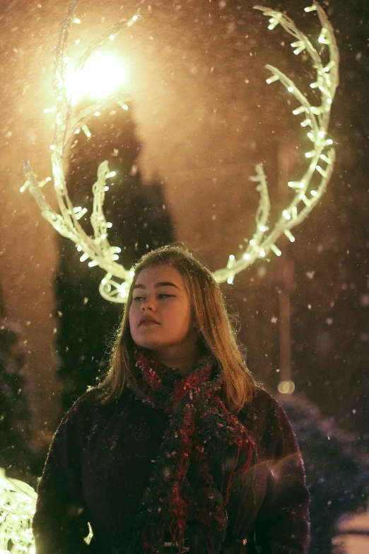 a woman standing in front of a christmas tree, inspired by Elsa Bleda, pexels contest winner, symbolism, antlers on her head, cinematic outdoor lighting, snapchat photo, ornamental halo