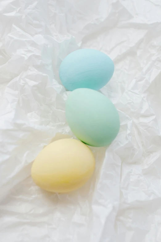 three eggs sitting next to each other on a piece of paper, a pastel, two tone dye, matte finish, squishy, medium-shot