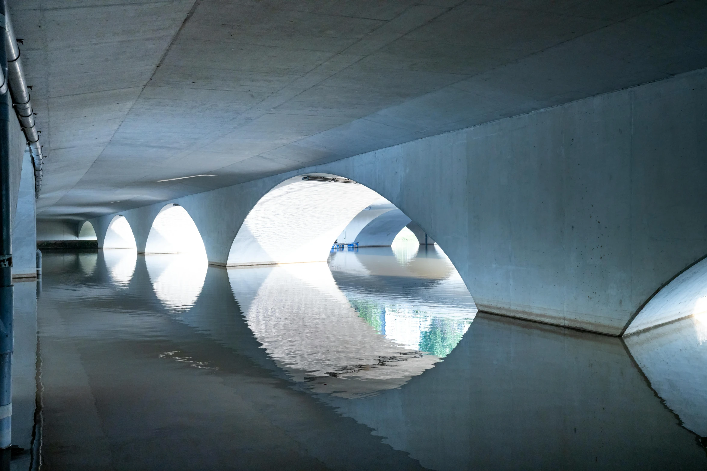 a man riding a skateboard under a bridge, inspired by Tadao Ando, unsplash contest winner, conceptual art, water mirrored water, underground, bjarke ingels, dramatic white and blue lighting