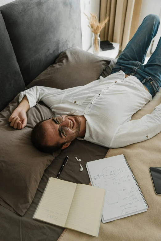 a man laying on top of a couch next to a laptop, pexels contest winner, happening, wearing a white button up shirt, happy friend, cozy bed, with notes