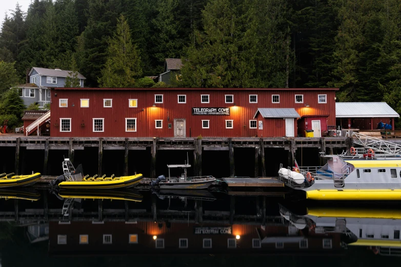 a number of boats in a body of water near a building, by Doug Wildey, pexels contest winner, vancouver school, tillamook cheese, cozy setting, 🦩🪐🐞👩🏻🦳, close to night