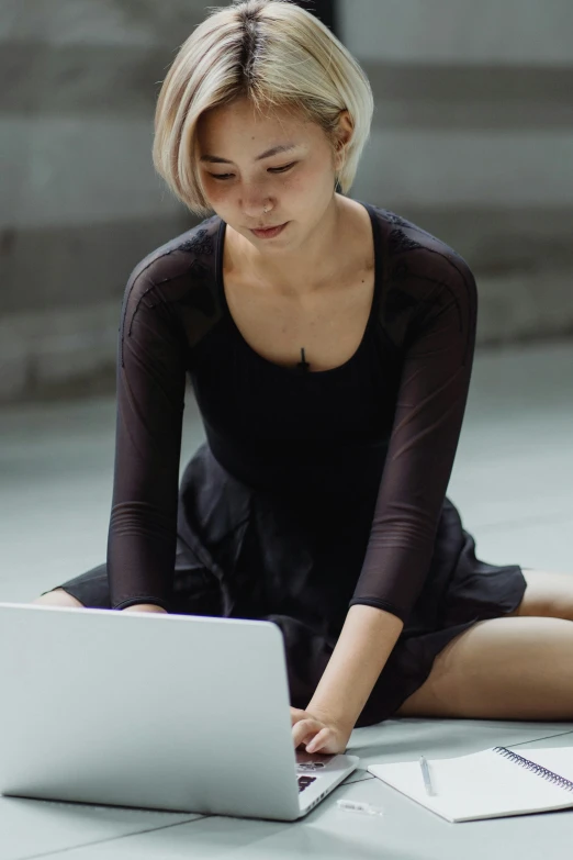 a woman sitting on the floor using a laptop, inspired by Elizabeth Polunin, trending on unsplash, renaissance, wearing black dress, a young asian woman, no - text no - logo, wearing leotard