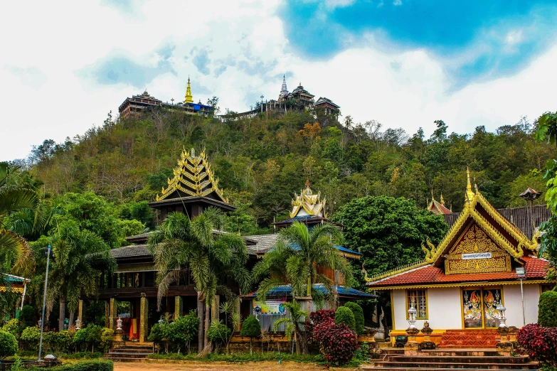 a group of buildings sitting on top of a lush green hillside, sumatraism, thai temple, multicoloured, square, teaser