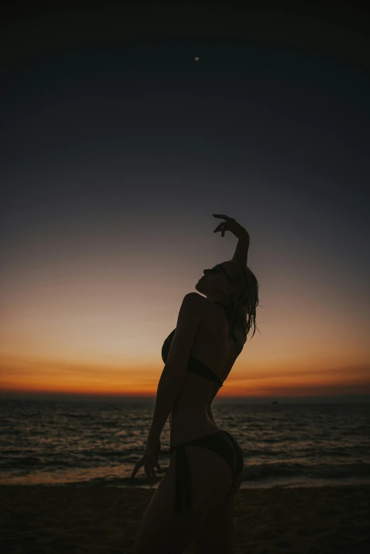 a woman standing on top of a beach next to the ocean, an album cover, trending on pexels, aestheticism, beautiful female body silhouette, summer night, dawn cgsociety, playful pose