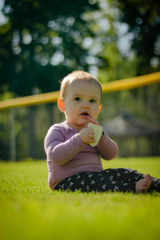 a baby sitting on top of a lush green field, female baseball player, 15081959 21121991 01012000 4k, having a snack, trending photo