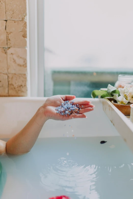 a woman sitting in a bath tub next to a window, trending on unsplash, floating crystals, hands, botanicals, sea foam