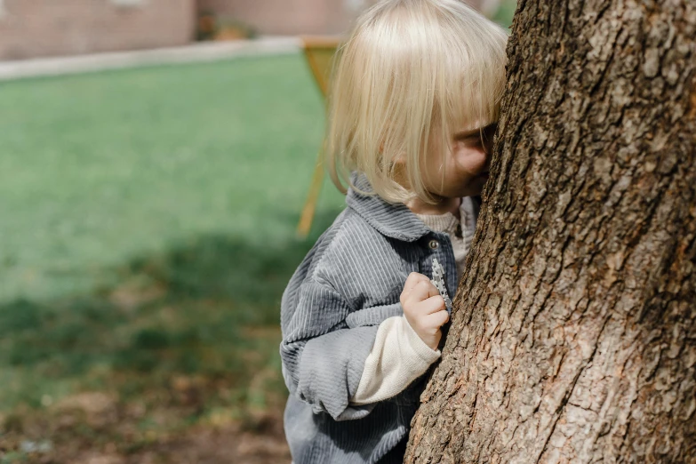 a small child standing next to a tree, pexels contest winner, photorealism, hiding, playing, close-up shot, 15081959 21121991 01012000 4k