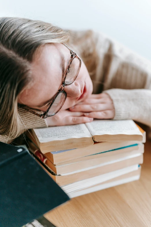 a woman laying her head on a stack of books, by Lynn Pauley, pexels contest winner, with closed eyes, very nerdy, sydney sweeney, chemistry