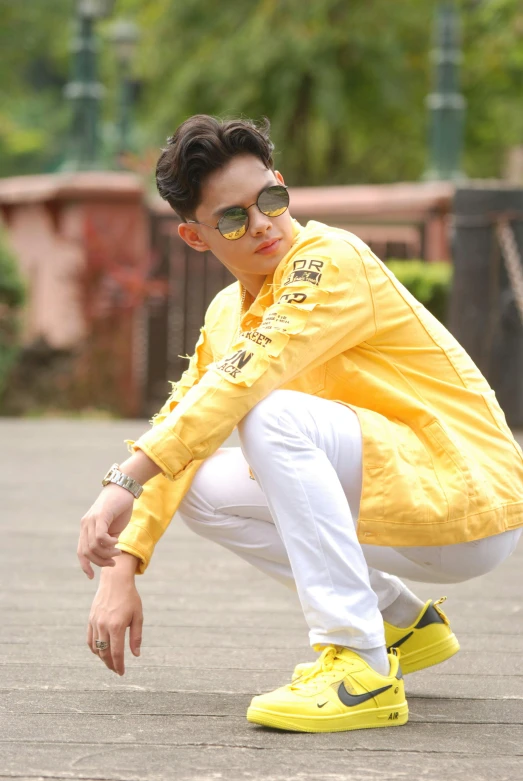 a man in a yellow jacket crouches down, by Basuki Abdullah, doing a sassy pose, teen boy, trending on imagestation, beautiful androgynous prince