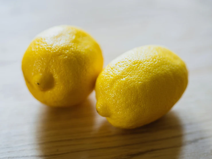 two lemons sitting next to each other on a table, pexels, taken with canon 5d mk4, round cheeks, made of glazed, loosely cropped