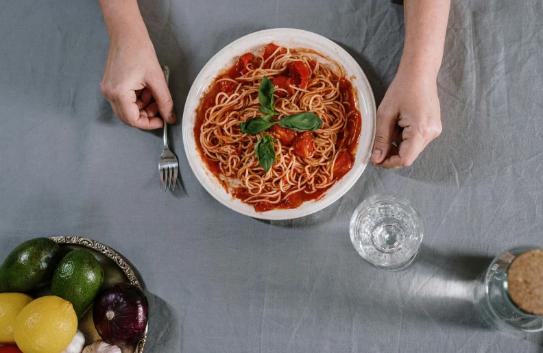 a person sitting at a table with a bowl of spaghetti, pexels contest winner, tomato sauce, offering a plate of food, minimalissimo, gif