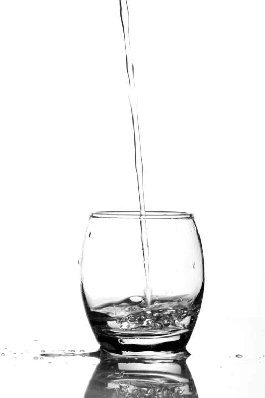 a glass filled with water sitting on top of a table, a black and white photo, by Hans Schwarz, pexels, 'white background'!!!, made of liquid, cascade, pouring