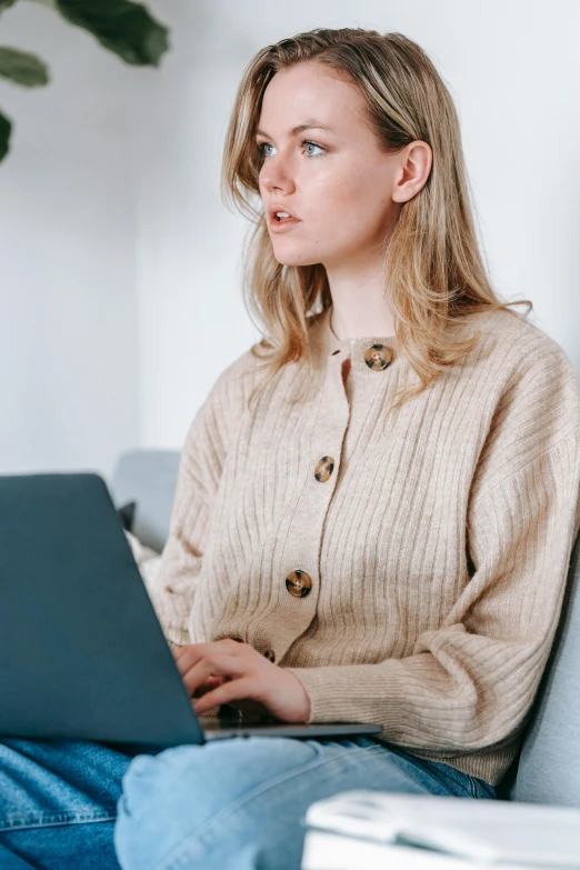 a woman sitting on a couch using a laptop, trending on pexels, renaissance, wearing a cardigan, close up of a blonde woman, reddit moderator, outfit photograph