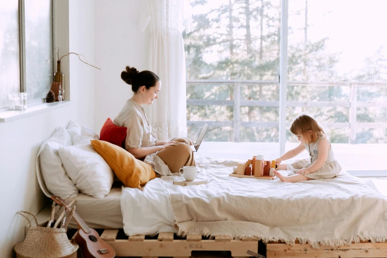 a woman sitting on top of a bed next to a little girl, pexels contest winner, sustainable materials, home office, manuka, 1 4 9 3